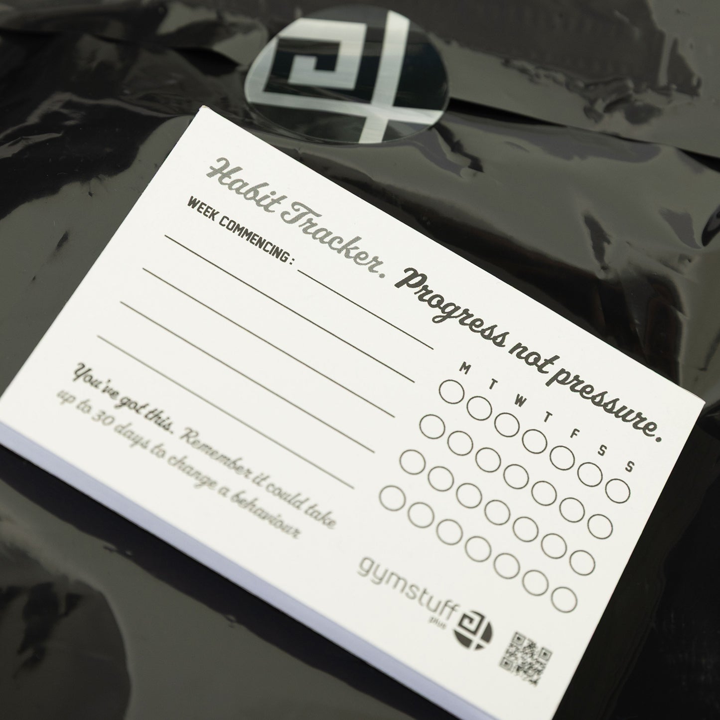 Gym Stuff Plus habit tracker pad with text 'Progress not pressure' on top of branded packaging, supporting plus size women’s fitness motivation.